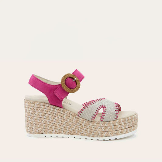 Profile view of a beige/pink wedge sandal with a woven platform and pink suede ankle strap, fastened by a circular buckle. 