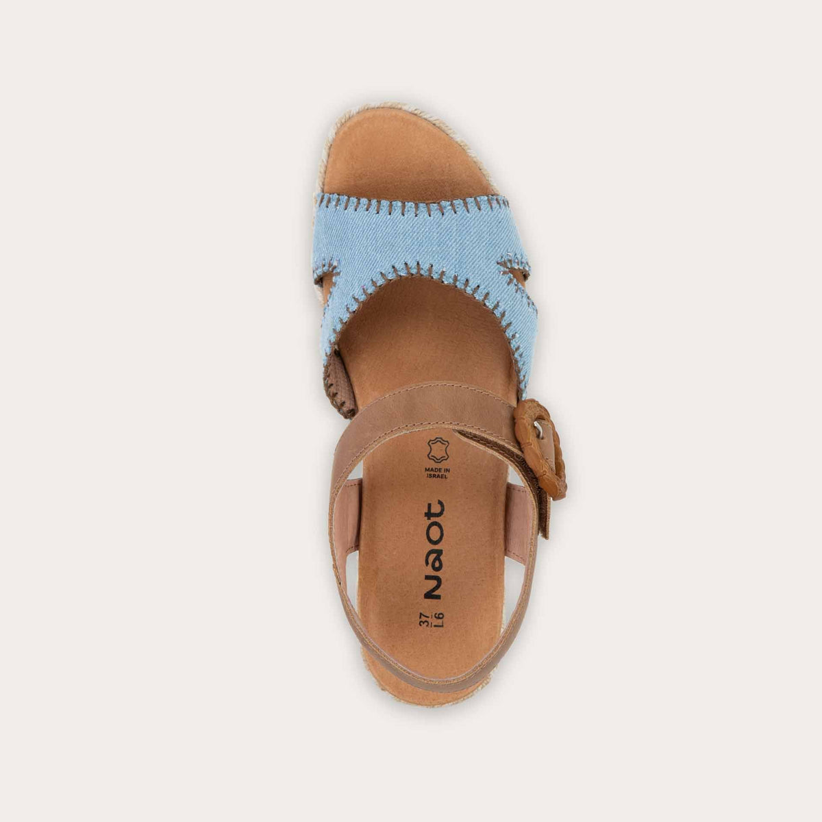 Top view of a blue/brown wedge sandal with a woven platform and brown leather ankle strap, fastened by a circular buckle. 