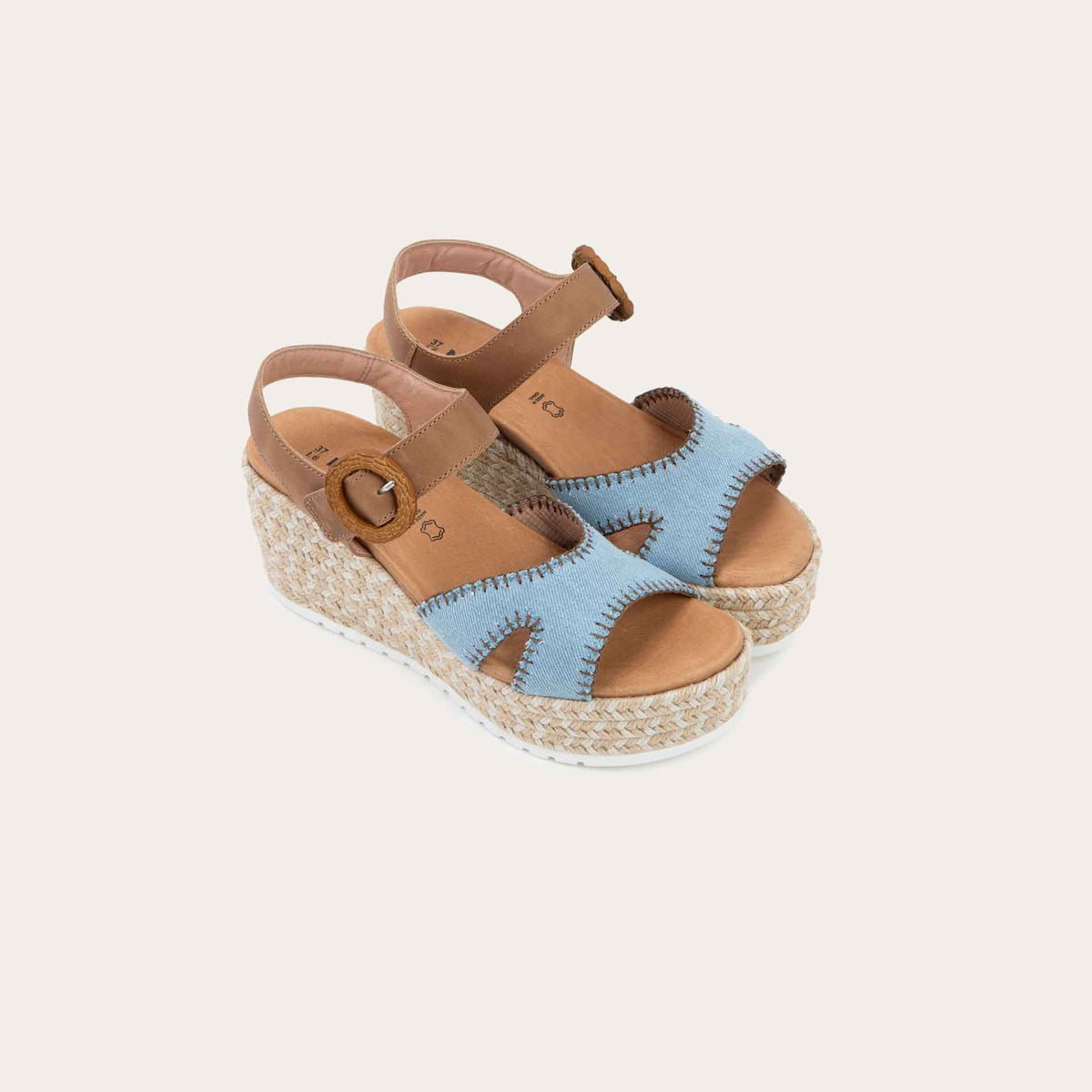 Pair of blue/brown wedge sandals with a woven platform and brown leather ankle strap, fastened by a circular buckle. 