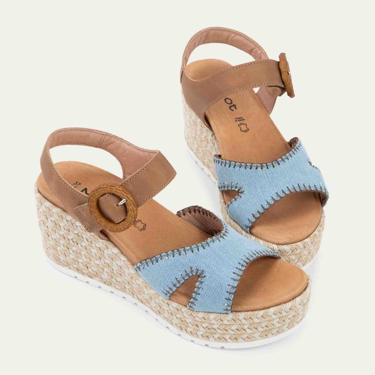 Pair of blue/brown wedge sandals with a woven platform and brown leather ankle strap, fastened by a circular buckle. 