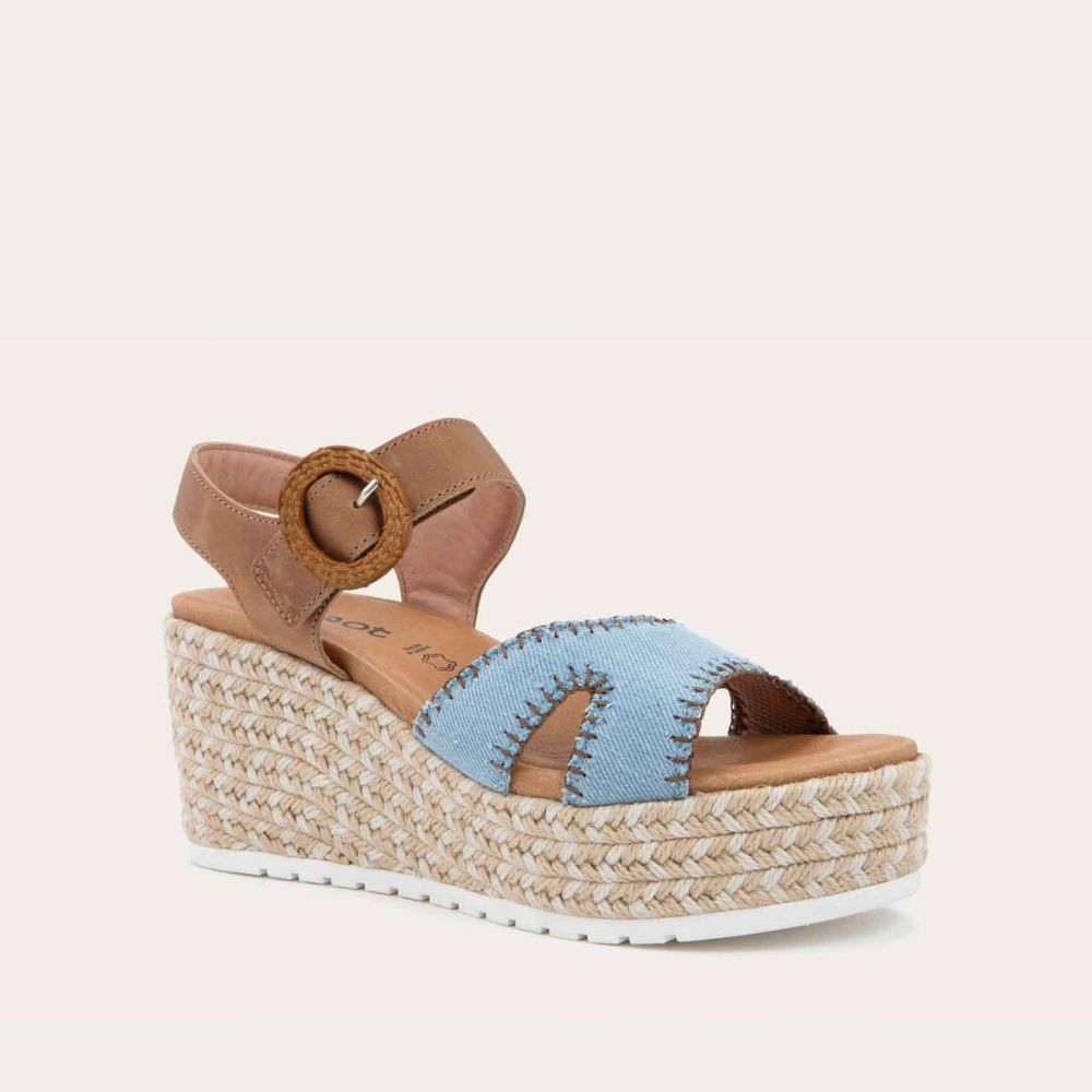 Angled profile view of a blue/brown wedge sandal with a woven platform and brown leather ankle strap, fastened by a circular buckle. 