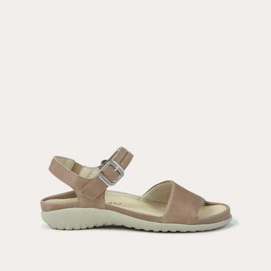 Profile view of a beige, open toe sandal, featuring a toe strap and asjustable ankle strap with a silver accent buckle.