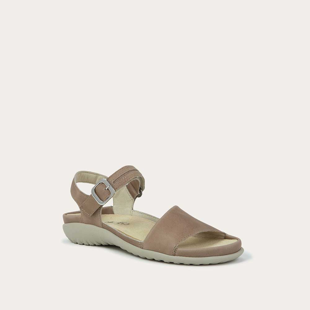 Angled profile view of a beige, open toe sandal, featuring a toe strap and asjustable ankle strap with a silver accent buckle.