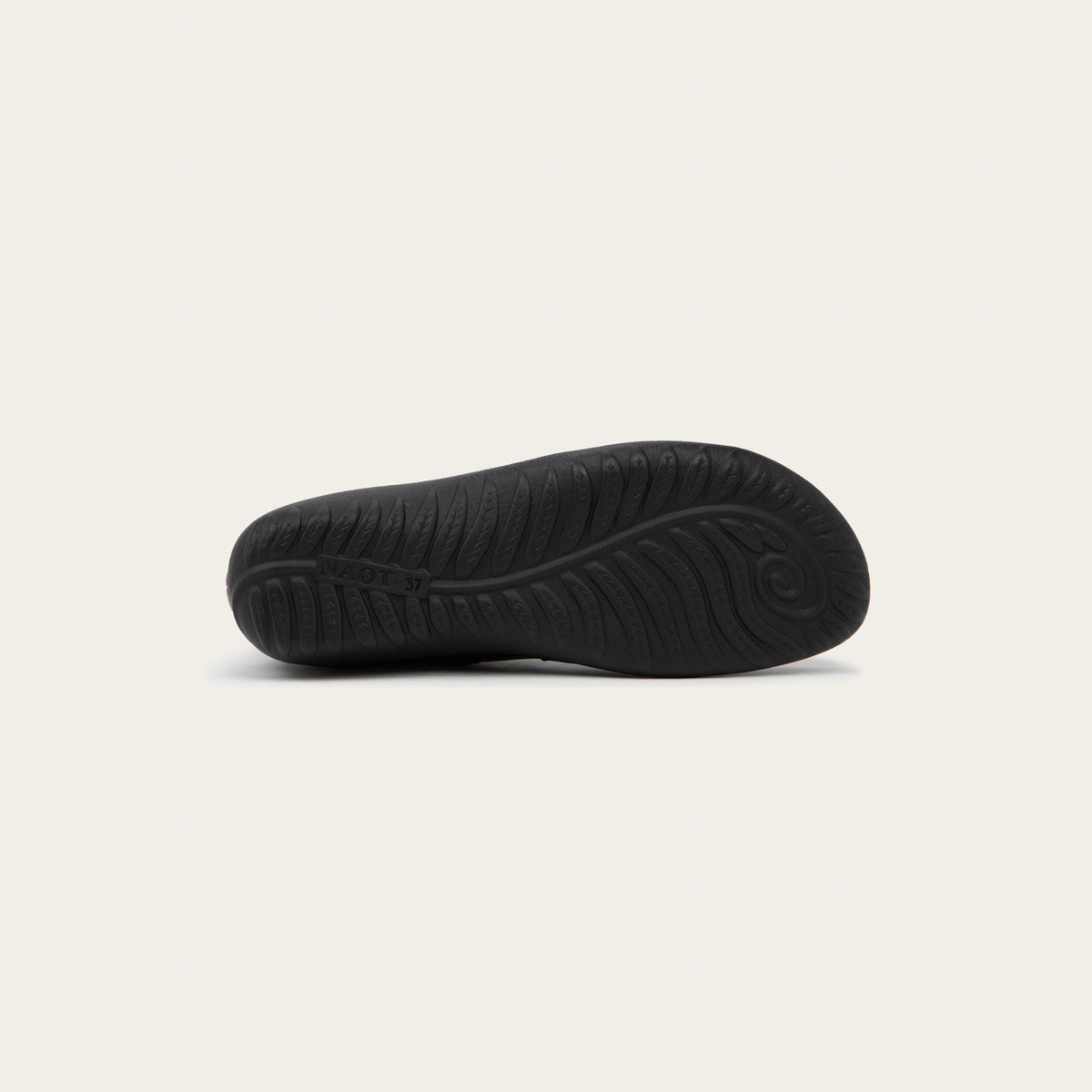 Bottom view of a black boot featuring an accent strap with round buckle in the back of the shoe on a dark sole.