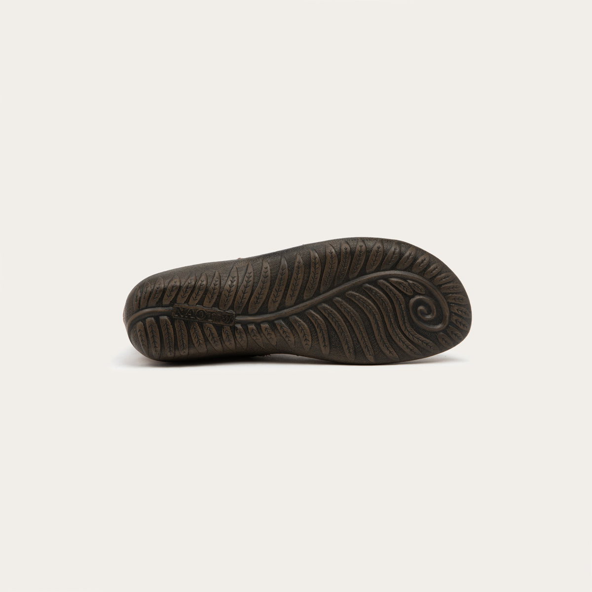 Bottom view of a brown boot featuring an accent strap with round buckle in the back of the shoe on a dark sole.