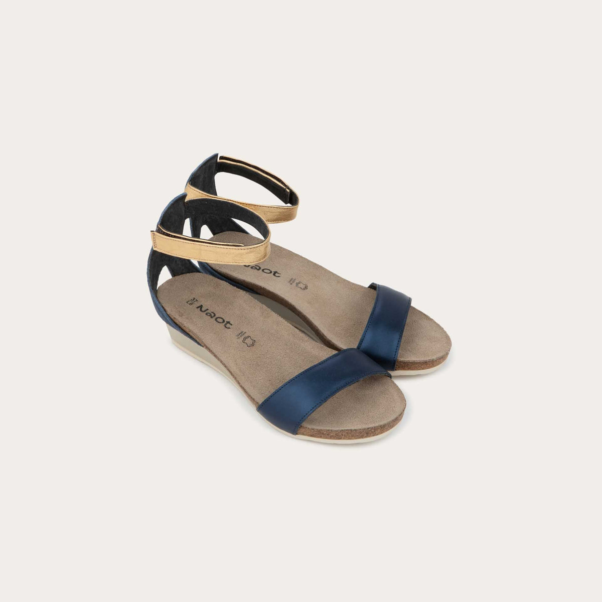Pair of blue wedge sandals with cork sole, featuring an open toe and metallic gold ankle strap.