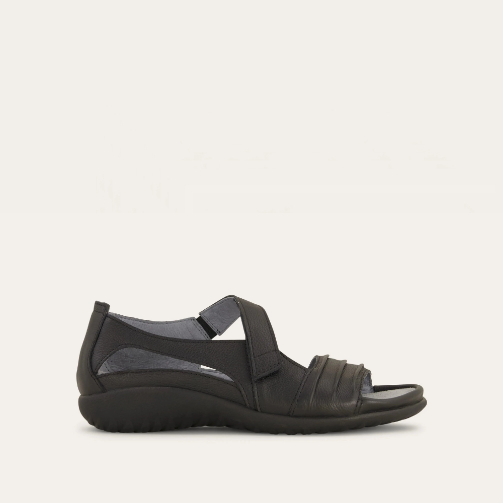 A black Papaki sandal by Naot, featuring a padded front strap, contrasting ruched detailing, and a hook and loop closure.