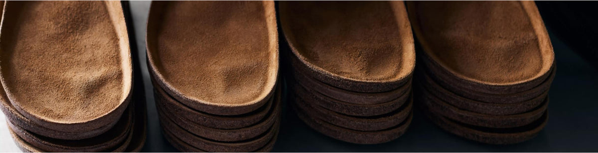 A close-up of stacked cork and suede footbeds, highlighting the quality materials and craftsmanship of the footwear.