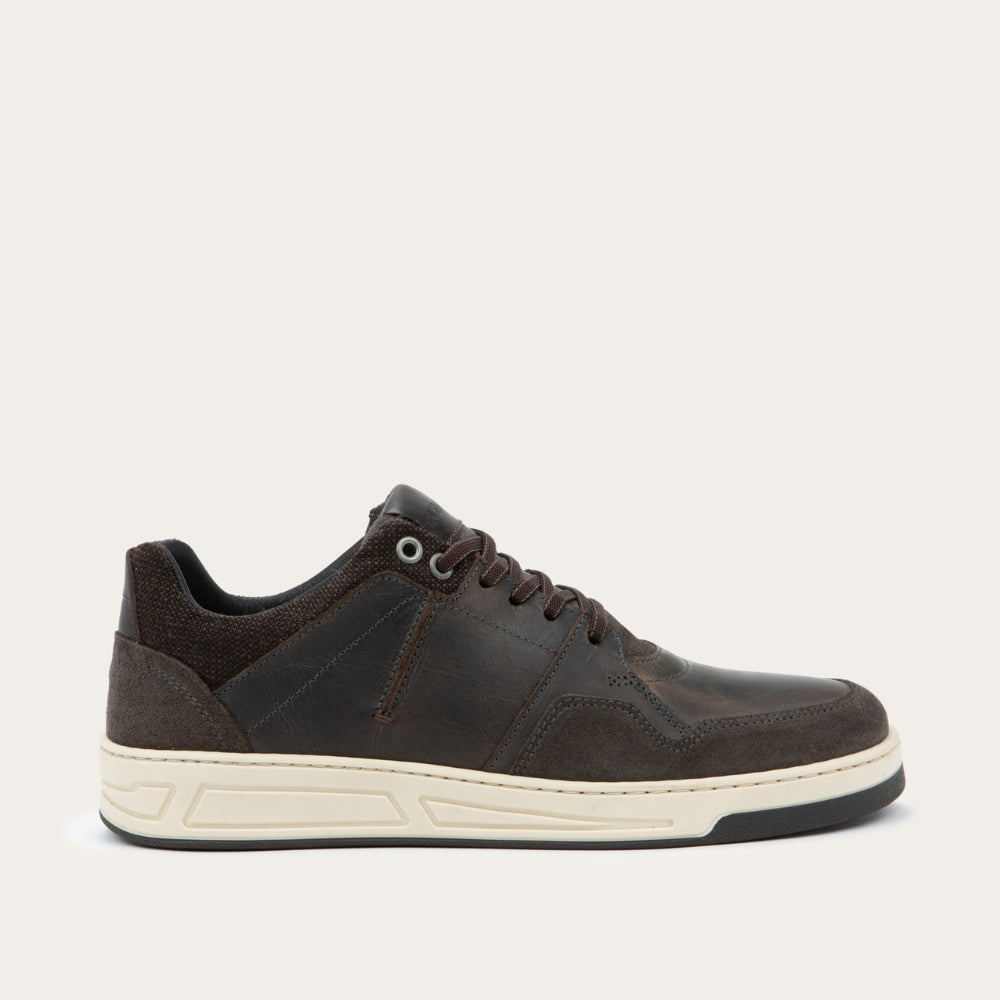 Side view of a gray sneaker with brown accents on a white sole.