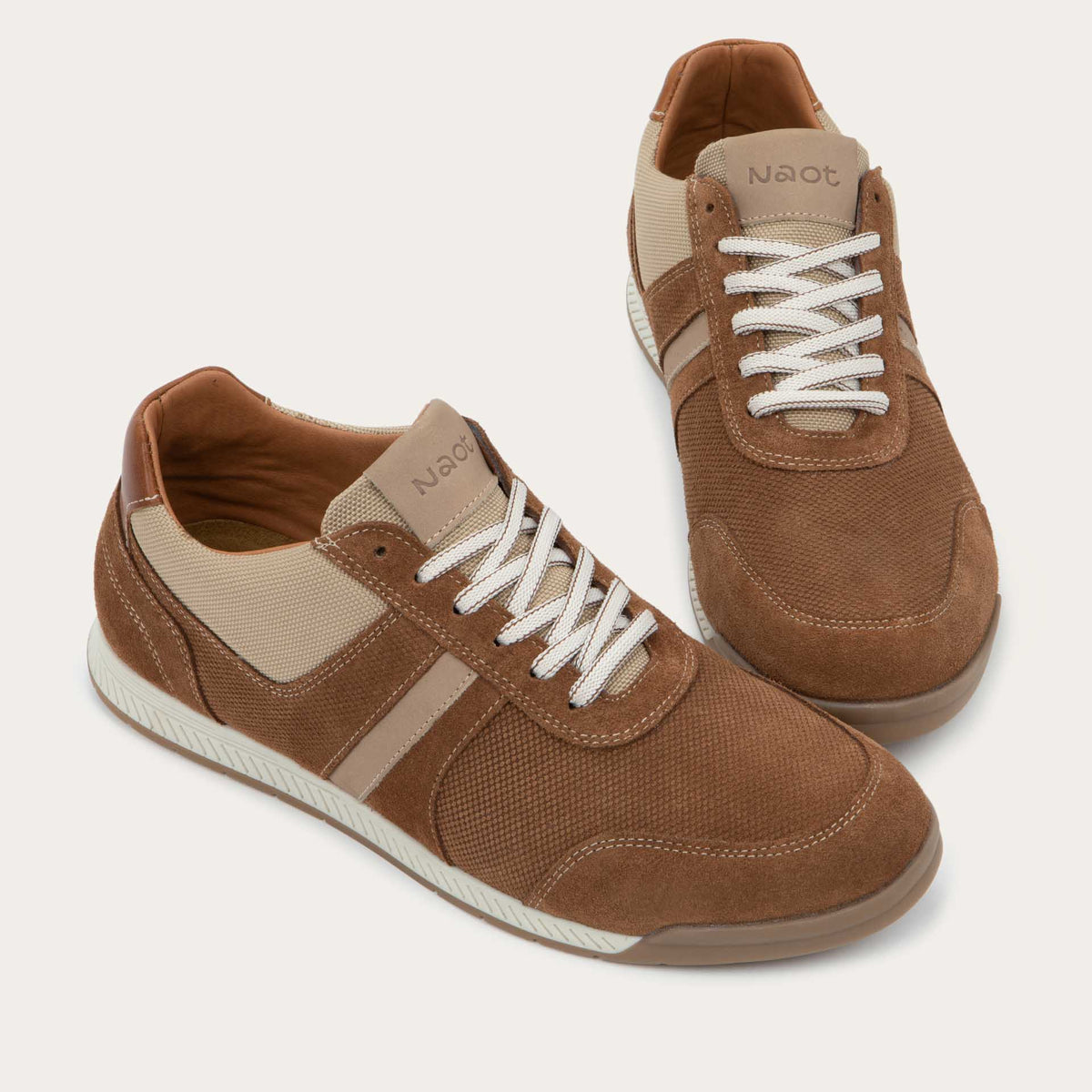 Pair of  brown and beige sneakers  on a brown sole.