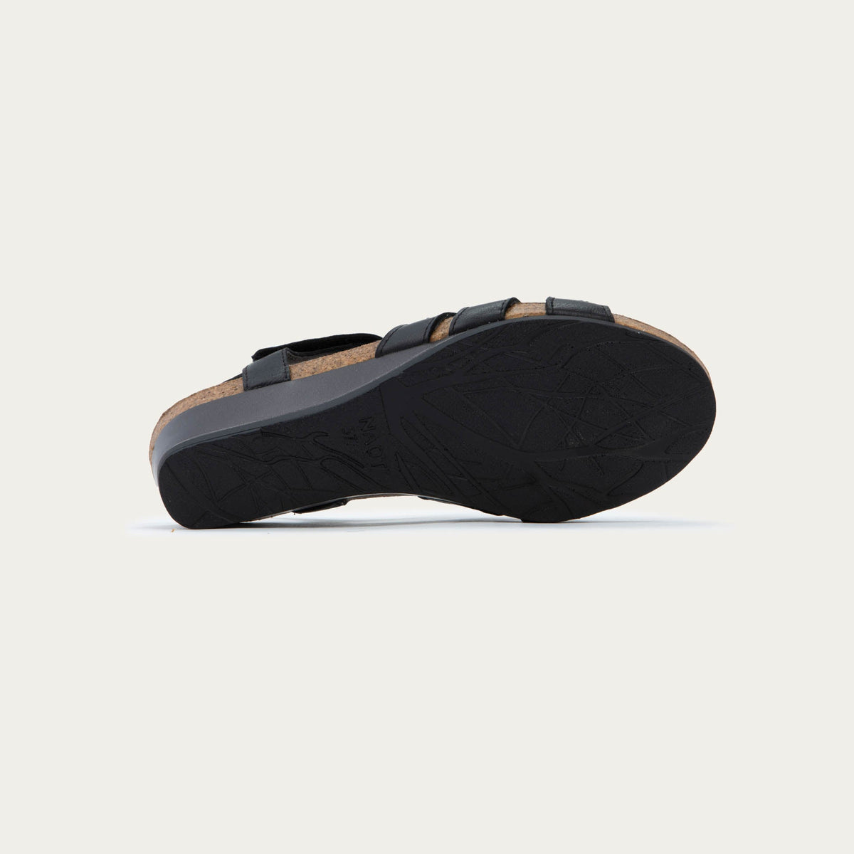 Bottom view of a  black wedge sandal with strappy design, open toe, and adjustable ankle strap on a cork footbed.