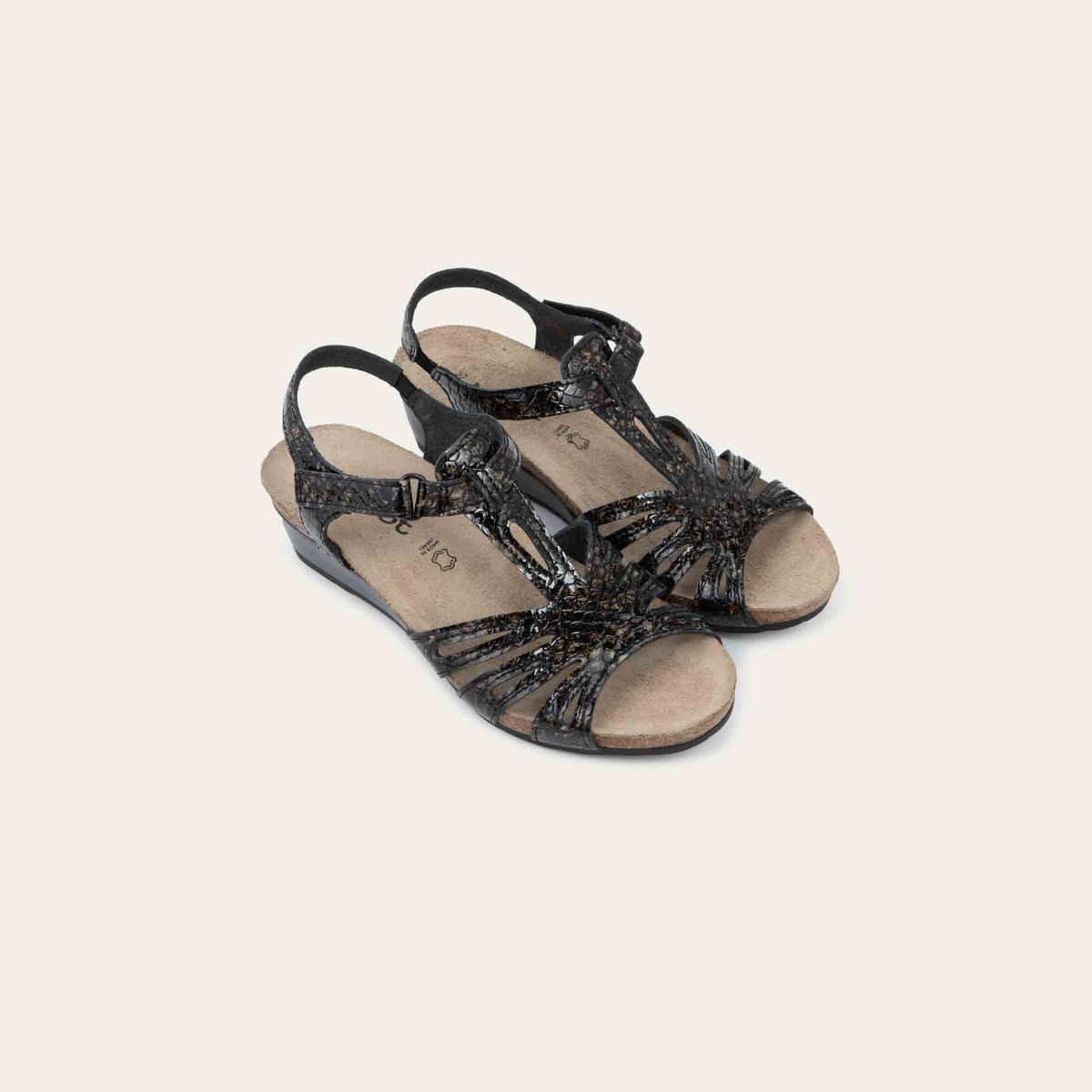 A pair of reptile printed wedge sandals with strappy design, open toe, and adjustable ankle strap on a cork footbed.