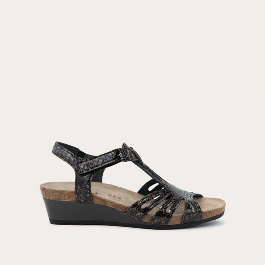 Profile view of a  reptile printed wedge sandal with strappy design, open toe, and adjustable ankle strap on a cork footbed.