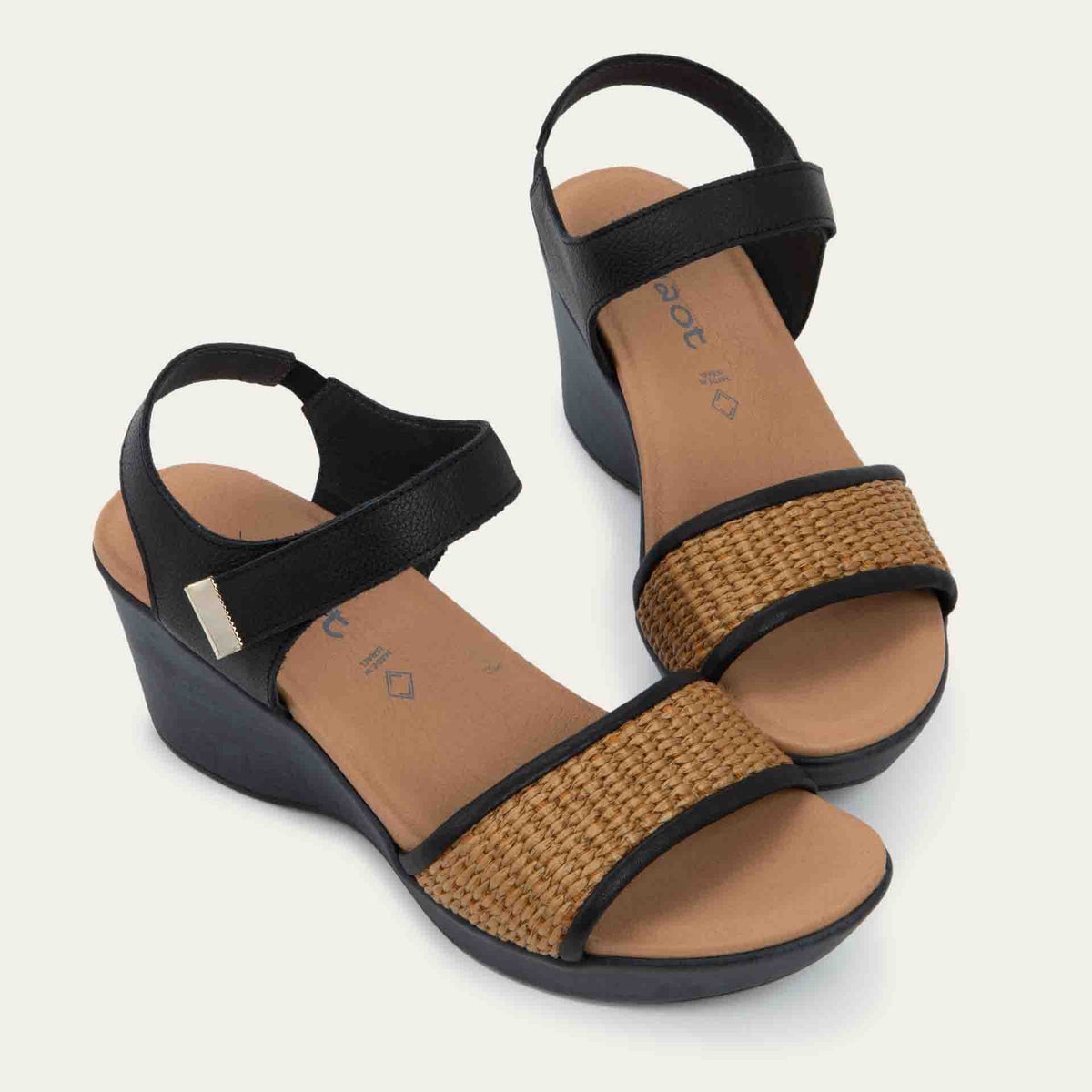 Pair of wedge heeled sandals with a black leather ankle strap, and woven tan front strap