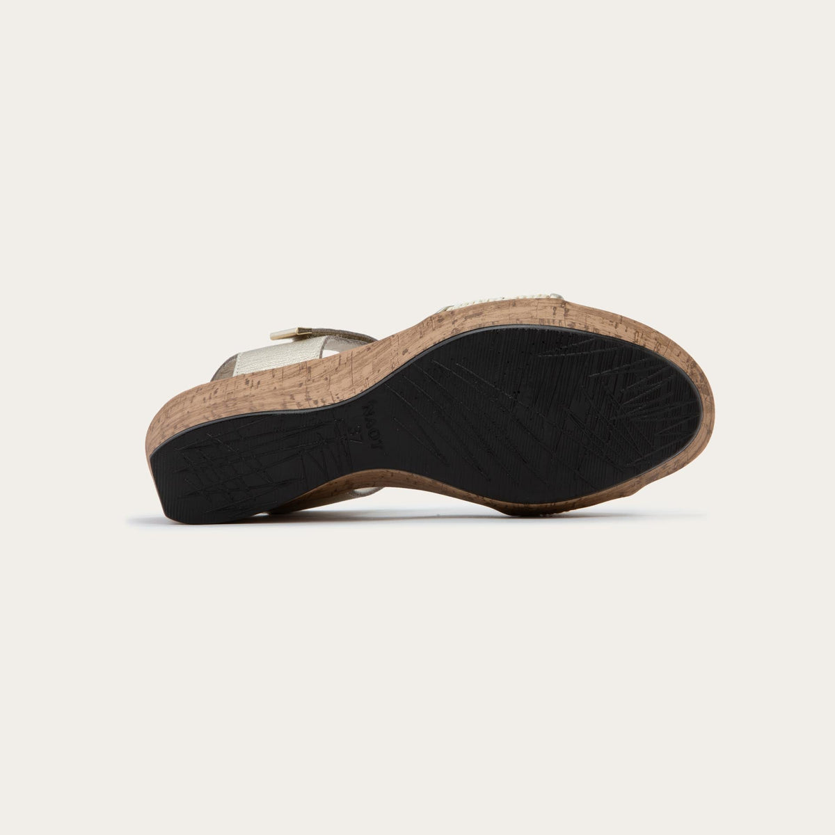 Bottom view of a wedge heeled sandal with a gold leather ankle strap, and woven beige front strap