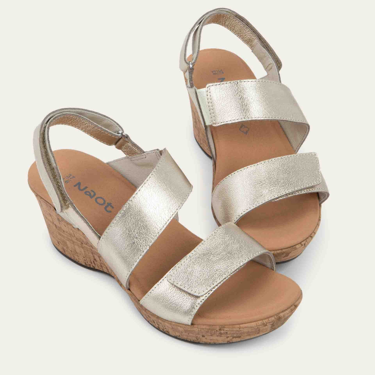 Pair gold sandals with metallic straps on a cork wedge sole. Features an open toe and wedge heel.