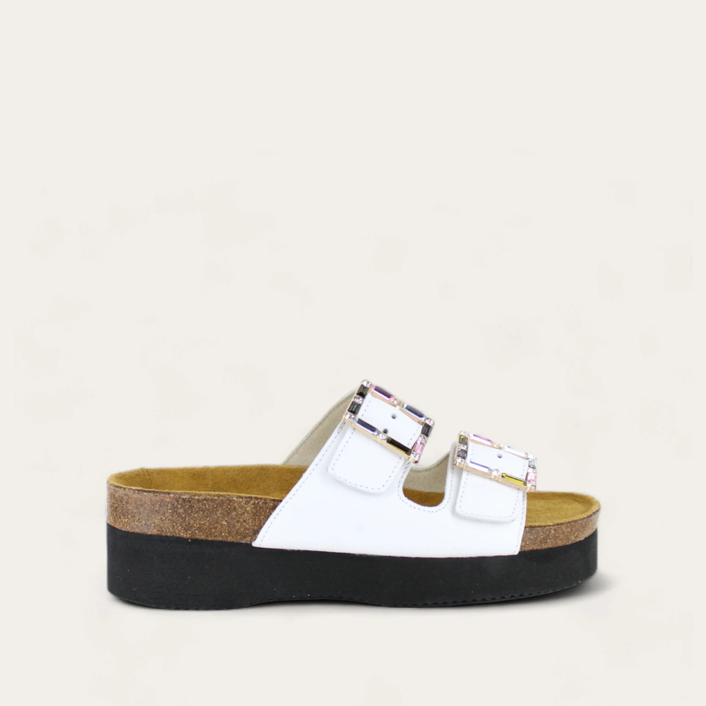 A pair of white Santa Rosa sandals with buckle details, on a cork footbed with a black sole.