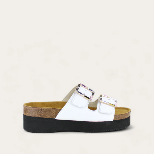 A pair of white Santa Rosa sandals with buckle details, on a cork footbed with a black sole.