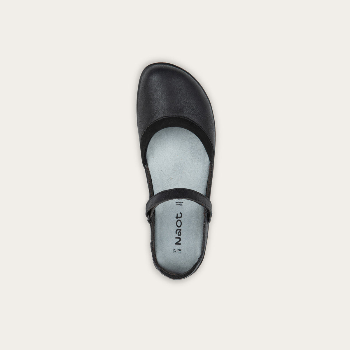 Top view of a black Mary Jane featuring contrasting materials and cutouts by the heel on a dark sole.