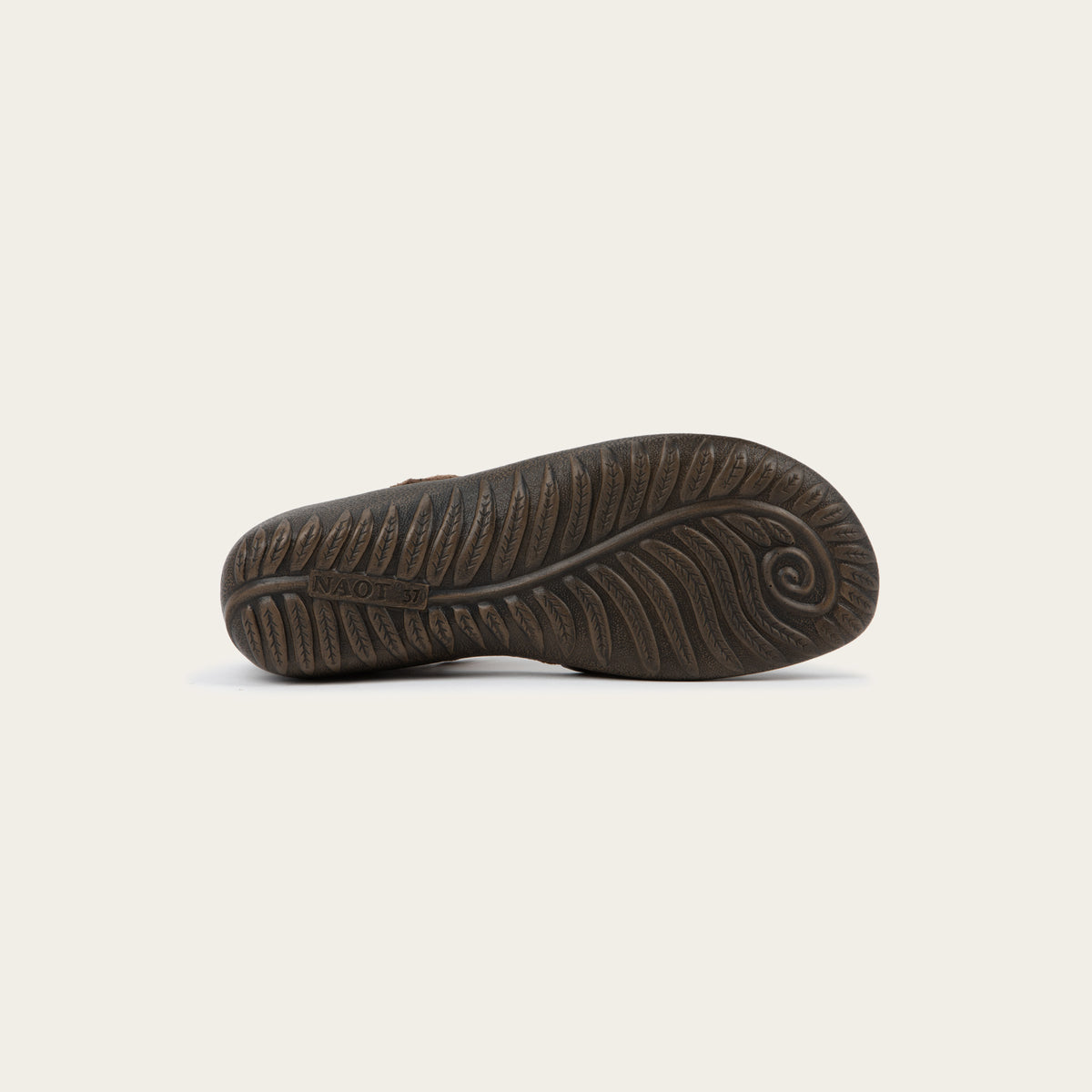 Bottom view of a brown Mary Jane featuring contrasting materials and cutouts by the heel on a dark sole.
