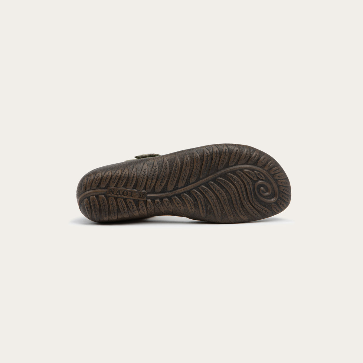 Bottom view of a green Mary Jane featuring contrasting materials and cutouts by the heel on a dark sole.