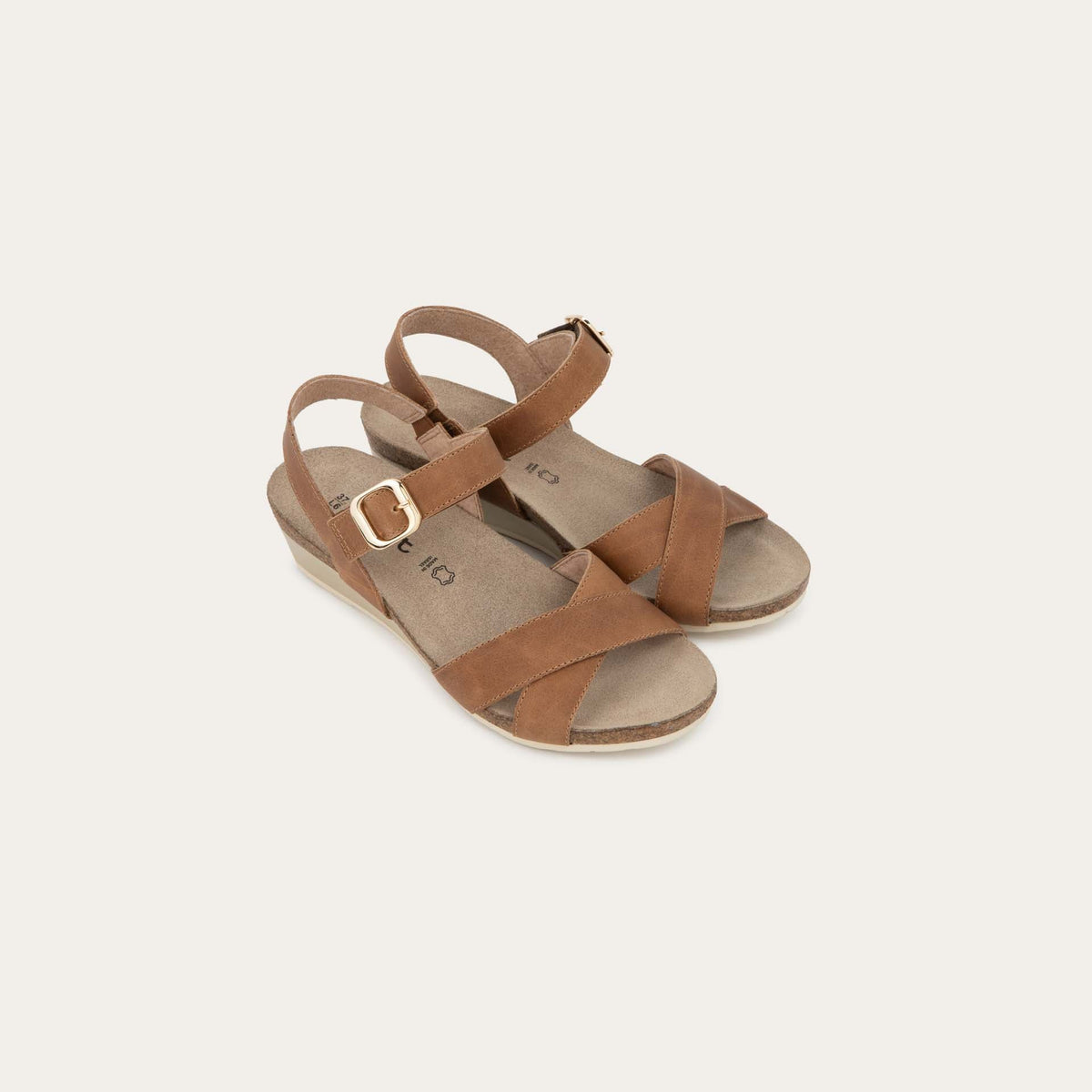 Pair of cork footbed,  brown wedge sandals with cross straps and a gold buckle on the ankle strap. 