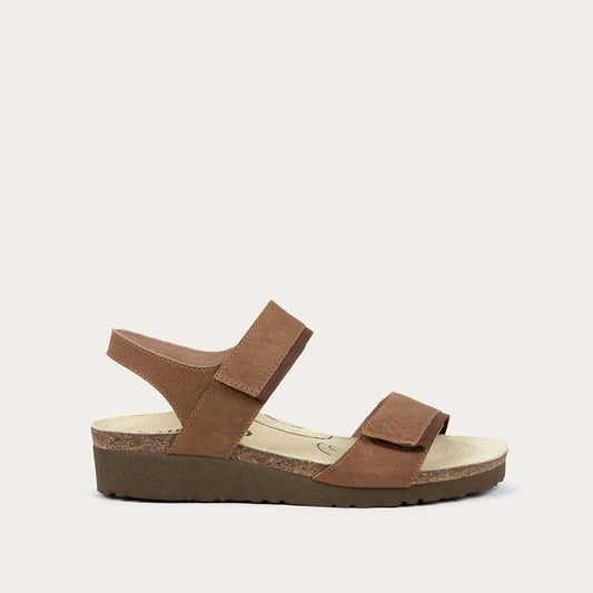 Profile view of a brown leather sandal with two adjustable straps and a cork platform sole.