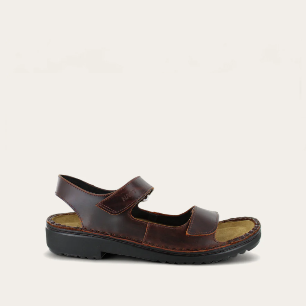A brown, adjustable sandal with hook and loop closures and side panels, on a white background.