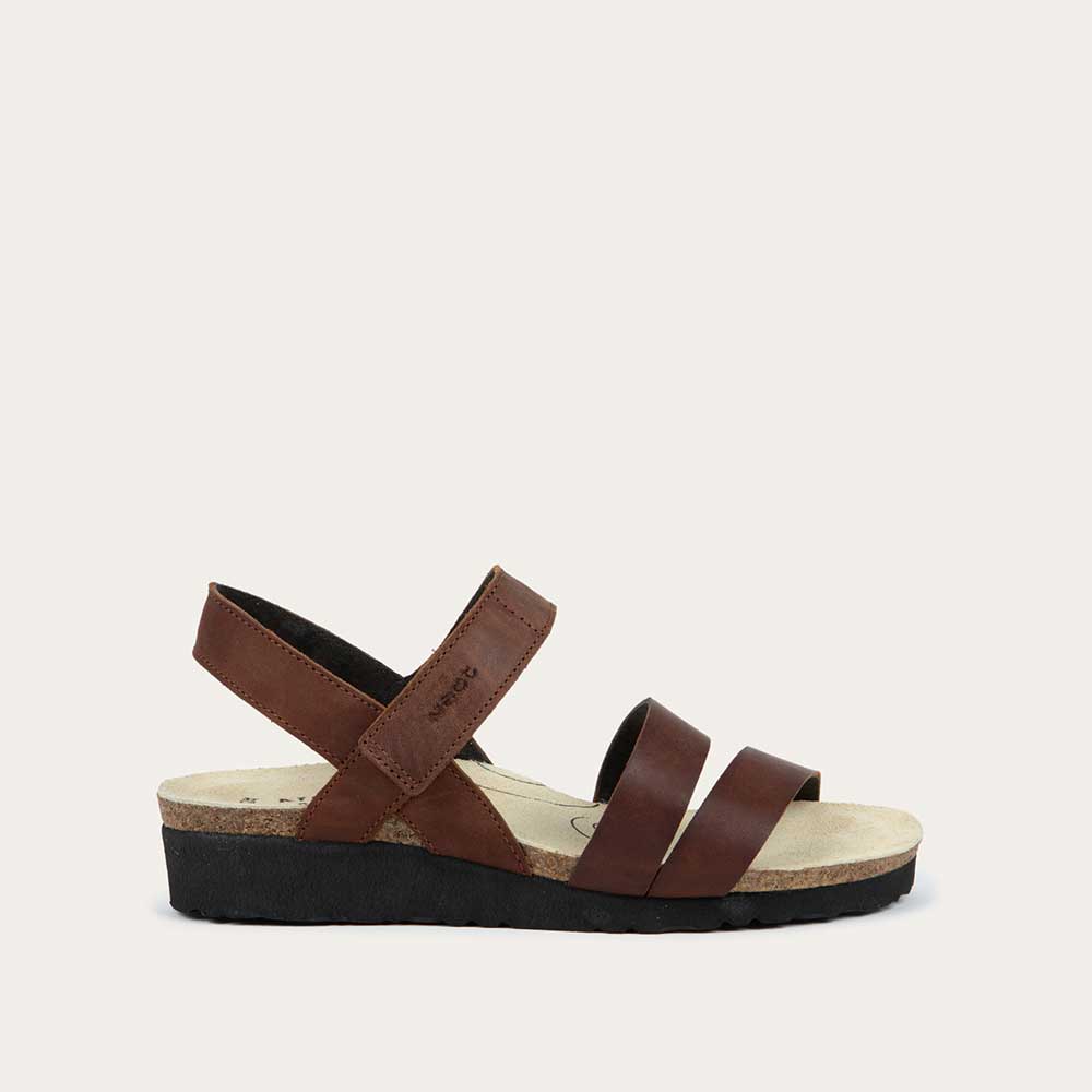 Profile view of a brown leather sandal with two toe straps, an adjustable ankle strap, and a cork platform sole.